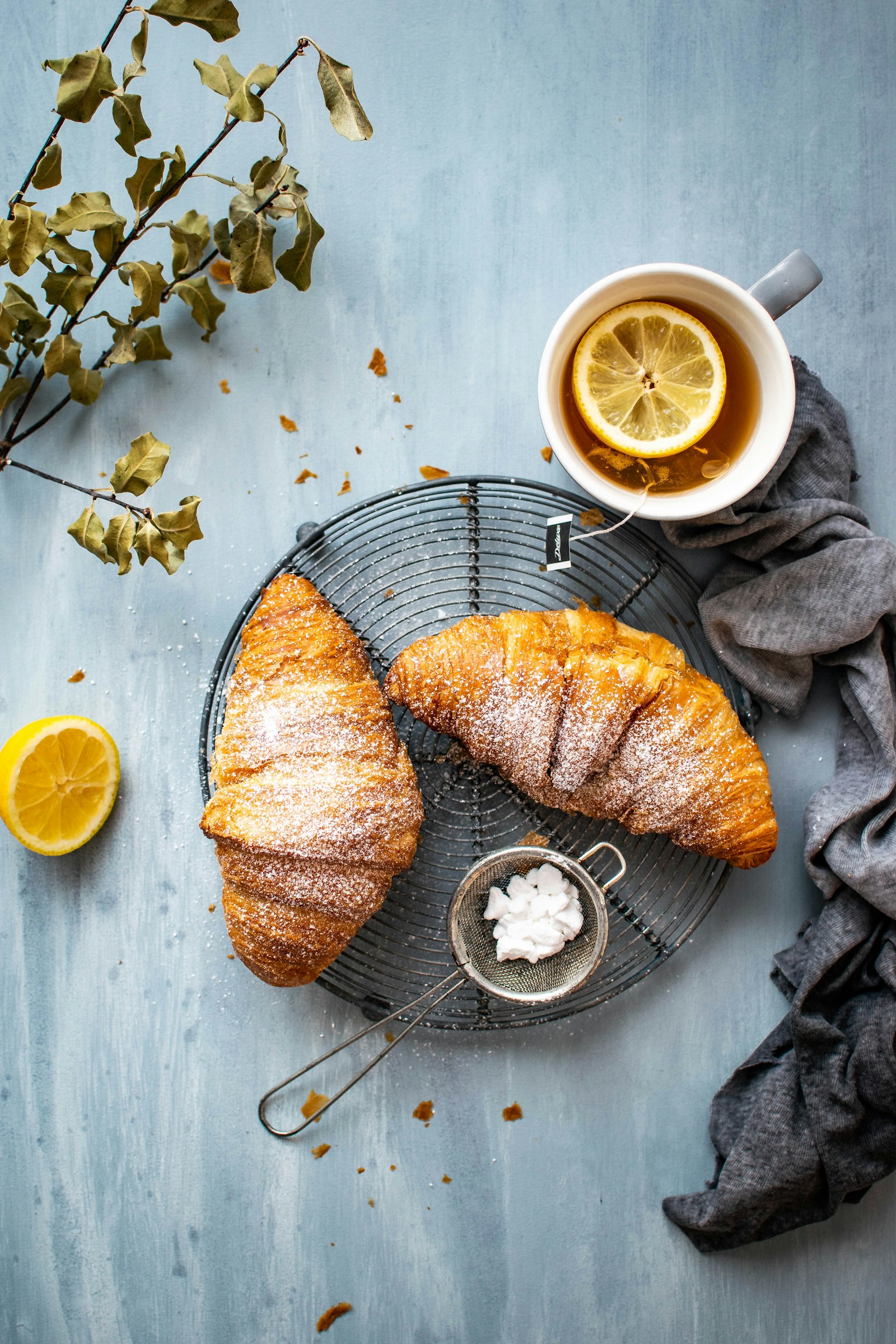Croissants con azúcar flor junto a una taza de té con limón